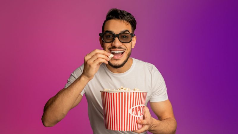 3dメガネをかけてバケットからポップコーンを食べているアラブ人の男性